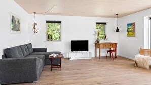 Ein modernes Wohnzimmer mit grauem Sofa, einem Holztisch und einem Fernseher.