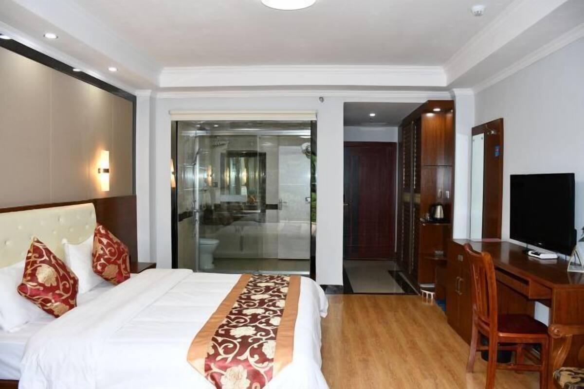 Een hotelkamer met een bed, een bureau, een televisie en een schuifdeur naar een balkon.