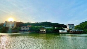 Imóvel à beira-mar com edifícios sobre palafitas, céu limpo e o sol se pondo ou nascendo.