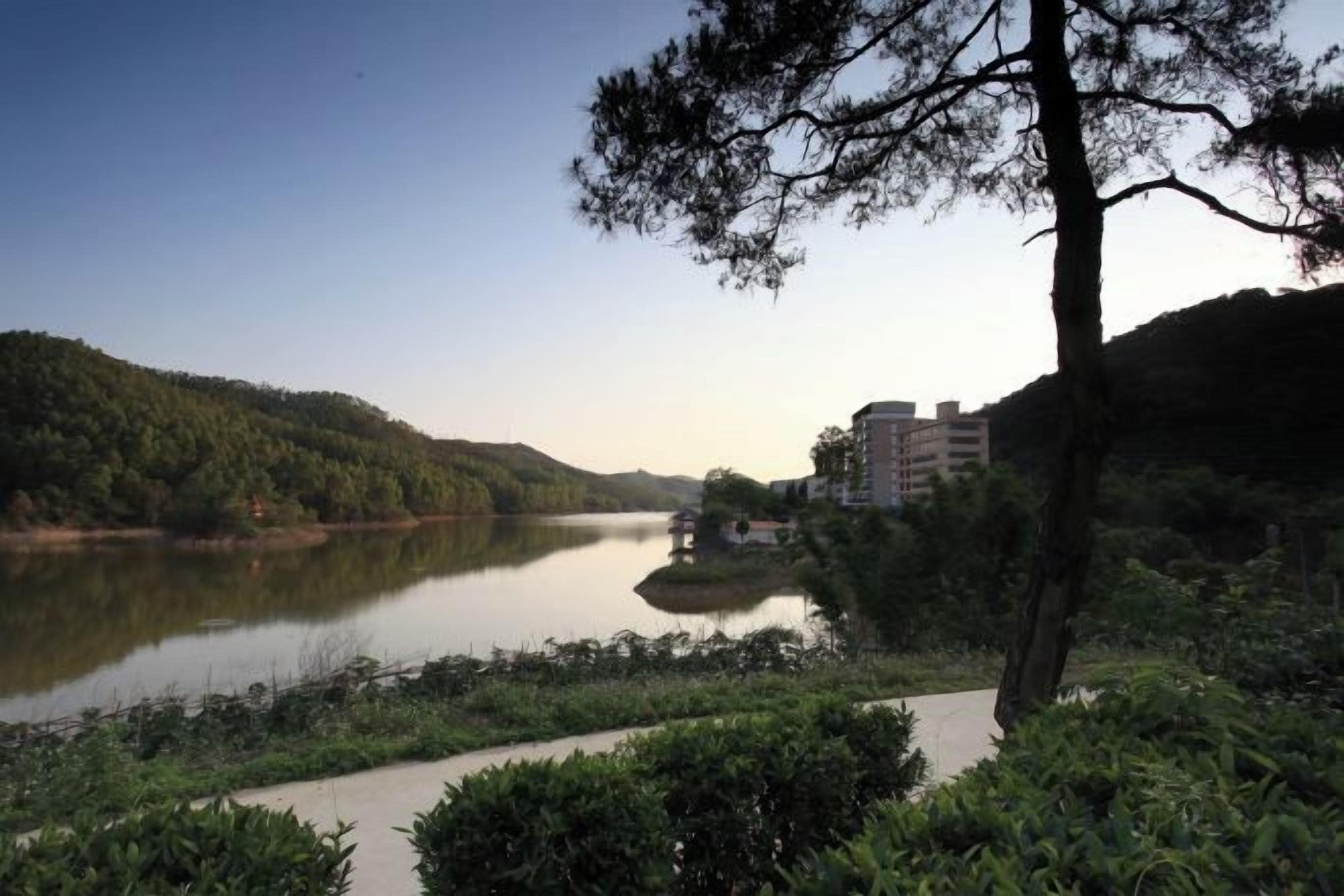 Une rivière avec un bâtiment sur la rive droite, entouré de verdure.