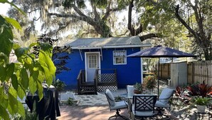 Une maison bleue avec un porche, des sièges d’extérieur et des plantes en pot.