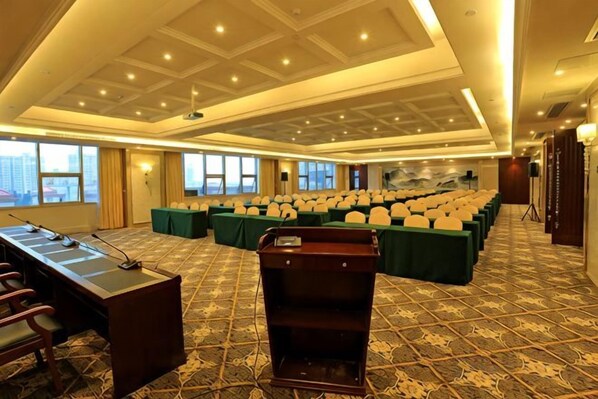 Une salle de conférence avec une longue table, des rangées de chaises et un pupitre.