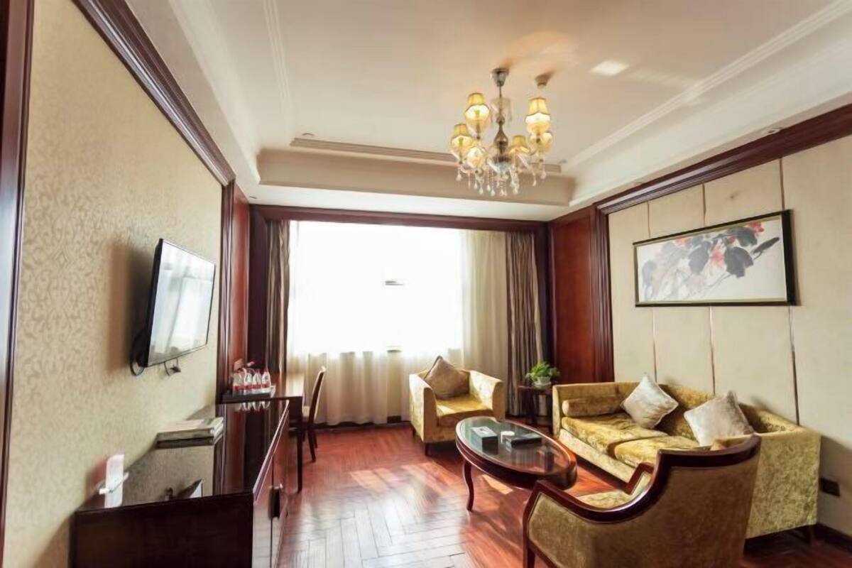 Une chambre d’hôtel équipée d’une télévision, d’un canapé, d’une table basse et d’un lustre.