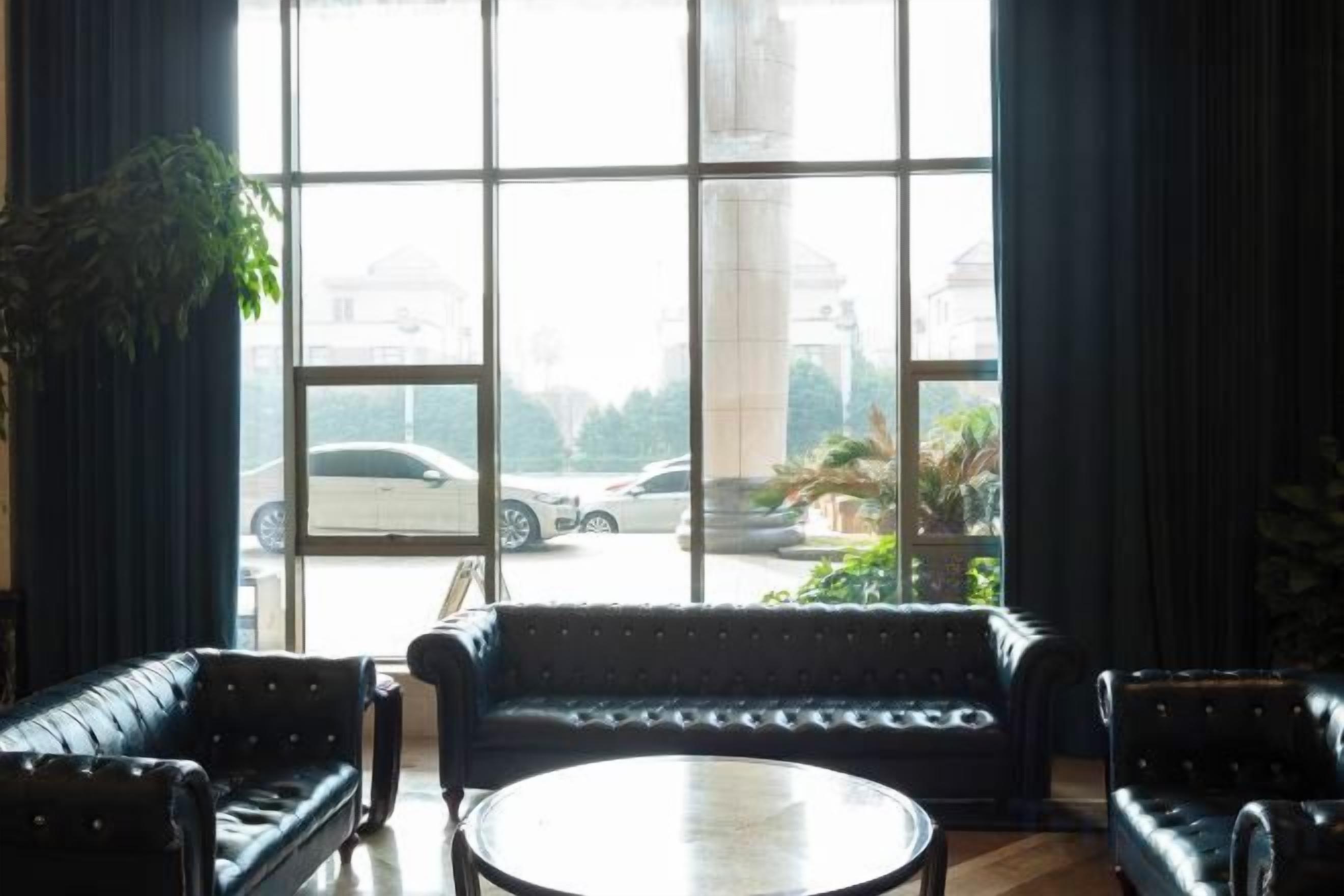 A room with a large window, a round table, and two sofas.