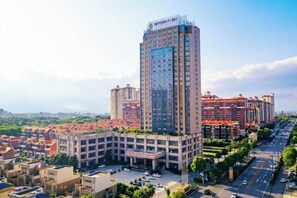 A high-rise building with multiple floors, surrounded by a parking lot and smaller buildings.