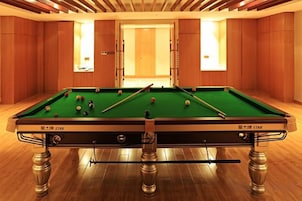 Una mesa de billar con bolas en una habitación con paredes de madera y una puerta.