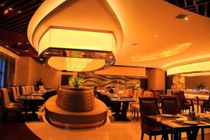 A restaurant with a central round table, multiple seating arrangements, and a large overhead light fixture. - Furong International Hotel (Yongxiu)