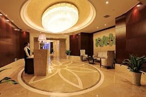 Un vestíbulo de hotel con mostrador de recepción, zona de estar y un gran diseño circular en el suelo.