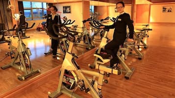 A gym with stationary bikes, mirrors, and wooden flooring.
