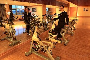 Une salle de sport équipée de vélos d’appartement, de miroirs et d’un plancher en bois.