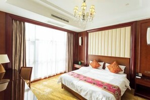 Una habitación de hotel con una cama grande, un candelabro, un escritorio y una silla.