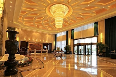 A spacious lobby with a grand chandelier, a reception desk, and a large window.. Furong International Hotel
