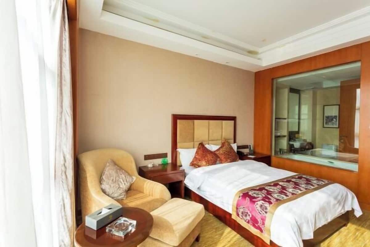 Une chambre d’hôtel avec un lit, une chaise, une table ronde et un grand miroir.