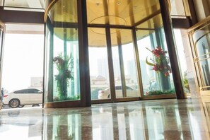 A hotel lobby with a glass entrance, a car parked outside, and a plant inside. - Furong International Hotel (Yongxiu)