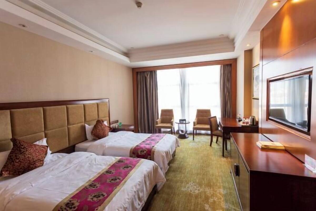 Une chambre d’hôtel avec deux lits, un bureau, une télévision et une vue sur l’extérieur.
