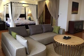 Ein Schlafzimmer mit einem Himmelbett, einem Sofa, einem runden Couchtisch und einem Schrank.