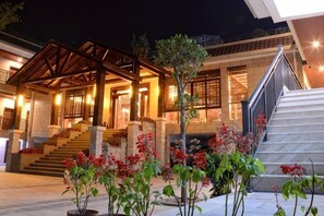 A hotel entrance with a covered porch, steps leading up to the main entrance, and potted plants in the foreground. - Wanning Hele Family Home Stay (Wanning)