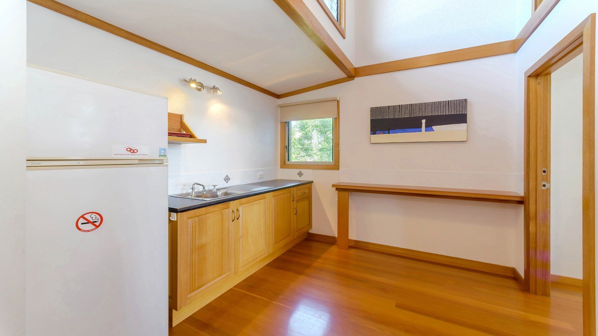A compact kitchen with wooden cabinets, a built-in sink, and a window with a view of greenery.