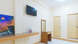 Hotellihuone, jossa on puinen työpöytä, seinälle asennettu televisio, peili ja kaksi ovea.