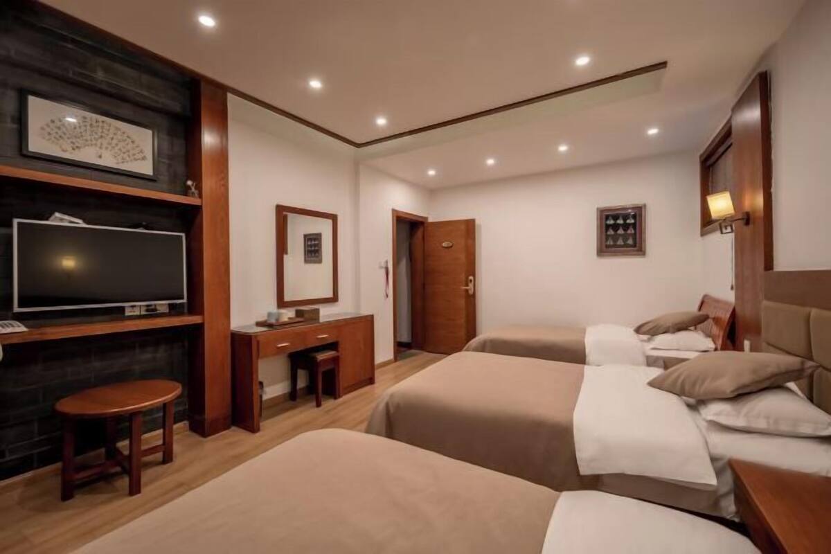 A hotel room with two beds, a desk, a television, and a small table.