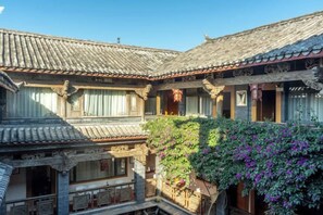 Une cour traditionnelle avec des toits en tuiles, des balcons en bois et une vigne grimpante.