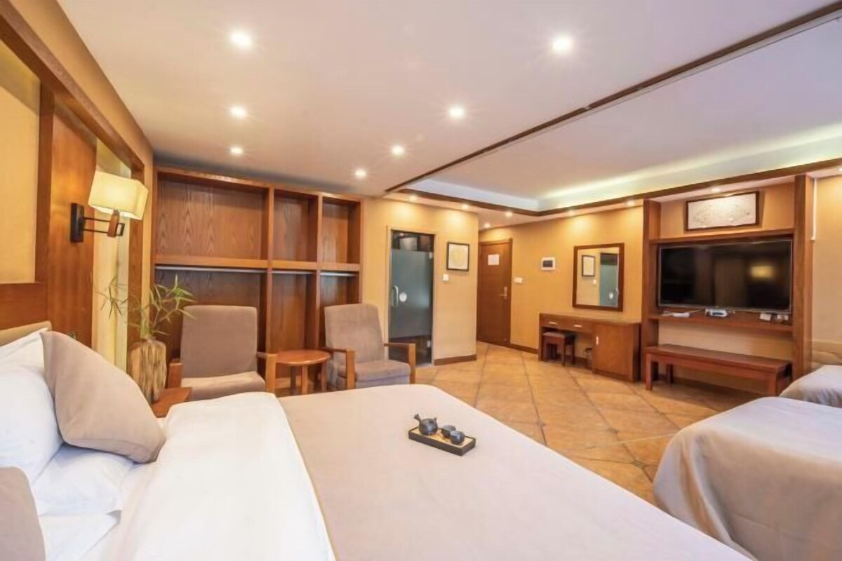 Ein Hotelzimmer mit einem großen Bett, einem Fernseher, einem Schreibtisch und einem Stuhl.