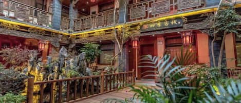 A multi-level atrium with wooden railings, potted plants, and a central staircase.
