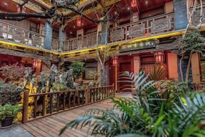 A multi-level atrium with wooden railings, potted plants, and a central staircase. - the Four Seasons the Inn (Lijiang)