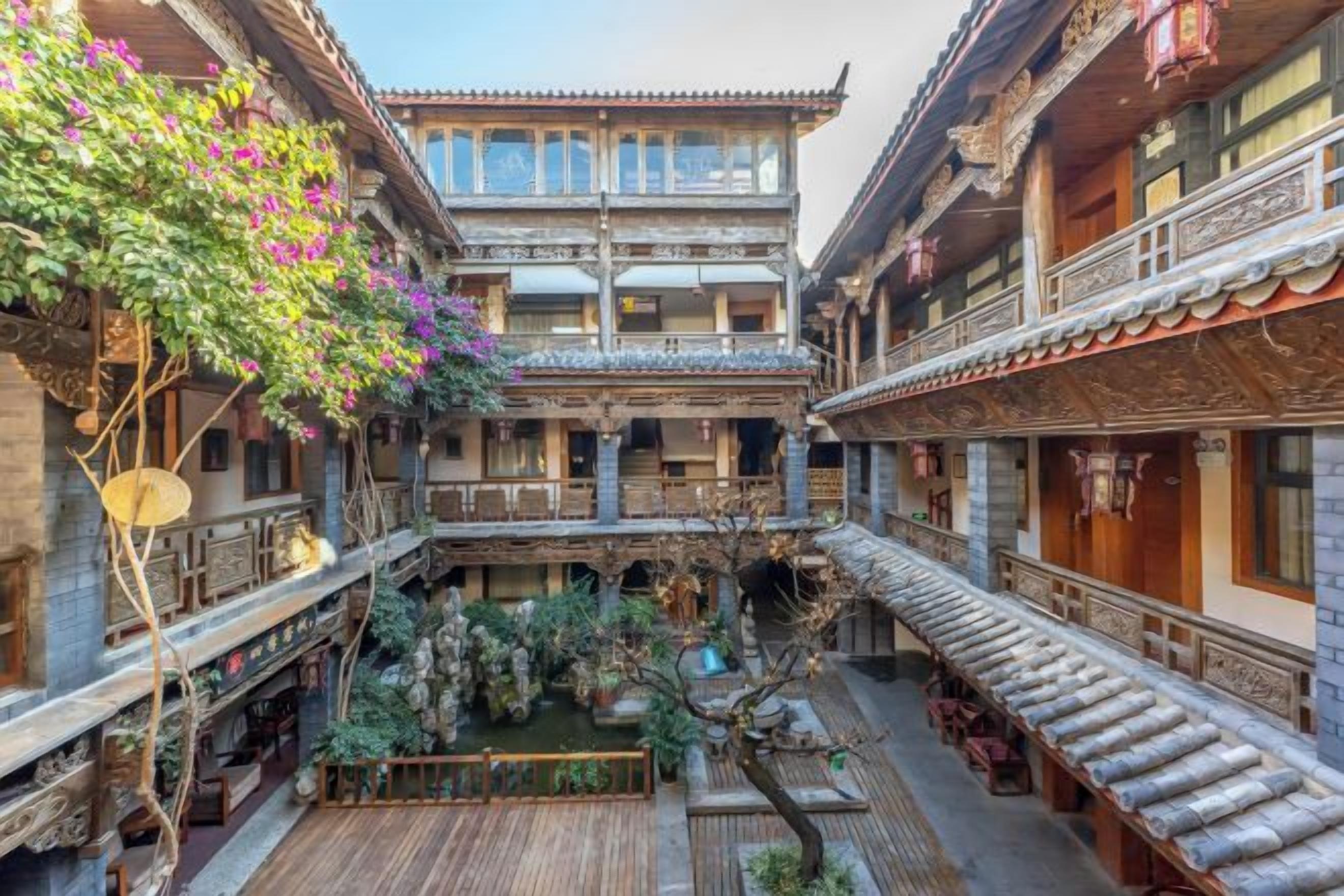 A traditional courtyard with multiple levels of buildings, wooden railings, and potted plants.
