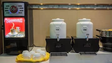 A coffee station with a cappuccino machine, two milk dispensers, and a yellow tray with cups.
