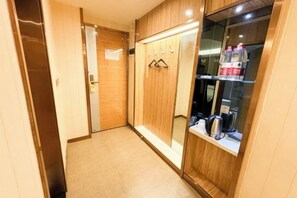 Un pasillo con un armario de madera, un espejo y una estantería con botellas.