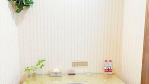 A small, clean room with a glass-top desk, a chair, a potted plant, a tissue box, a lamp, and two water bottles. - Super 8 Hotel Zepu Fatong Park (Zepu)