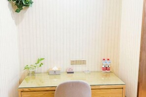 A small, clean room with a glass-top desk, a chair, a potted plant, a tissue box, a lamp, and two water bottles. - Super 8 Hotel Zepu Fatong Park (Zepu)