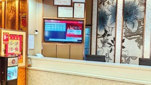 A reception desk with a digital display, framed certificates, and a floral-patterned wall. - Super 8 Hotel Zepu Fatong Park (Zepu)