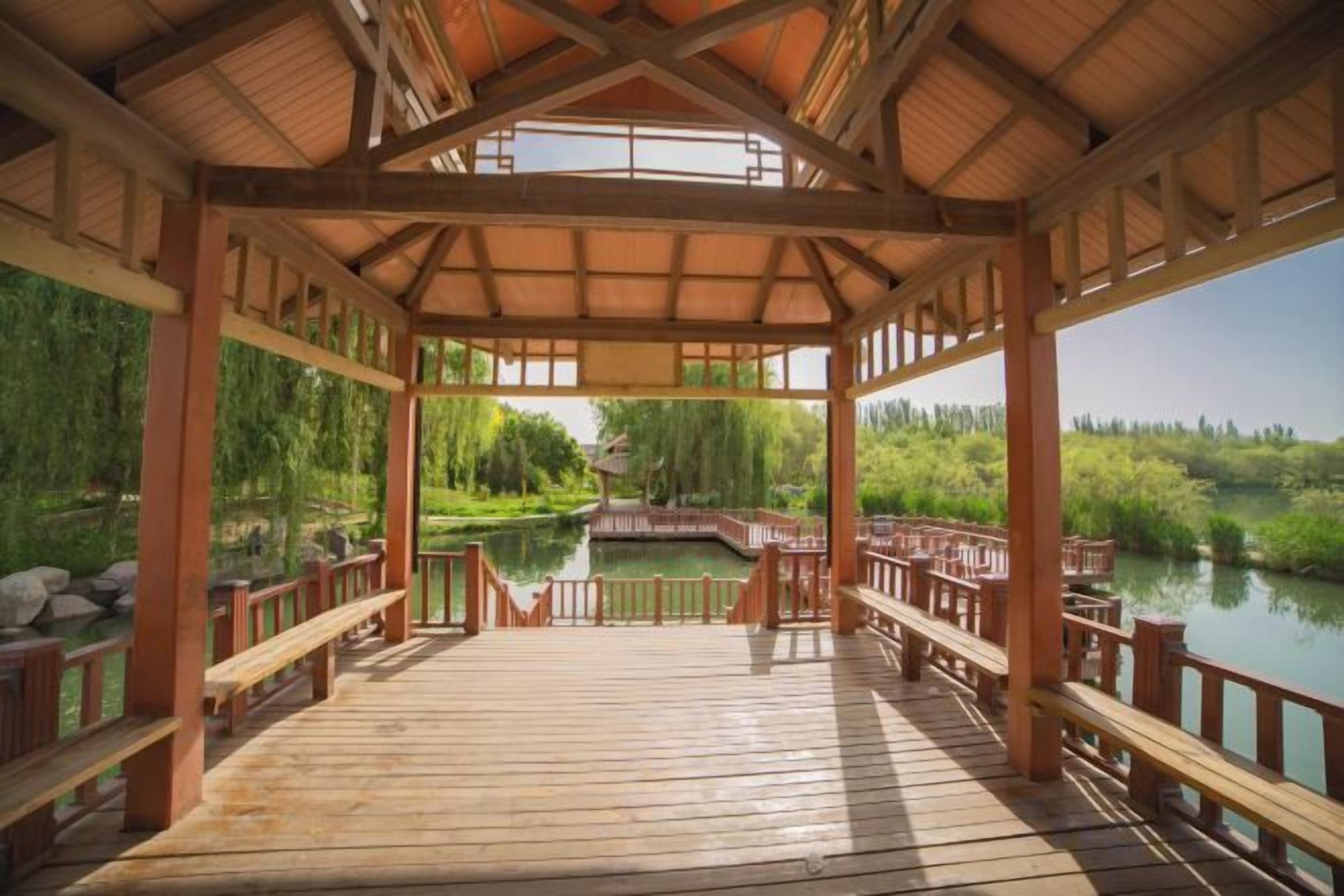 Una terraza de madera con vista a un estanque y árboles.