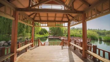 A wooden deck with a view of a pond and trees.