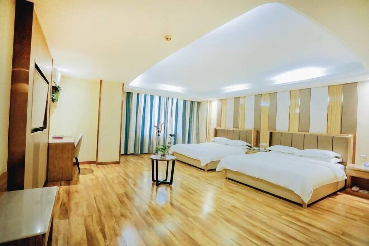 A hotel room with two beds, a desk, and a small table.