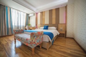 Una habitación de hotel con cama, sofá, escritorio y ventana con cortinas.