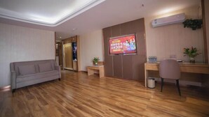 A modern living room with a wooden floor, a sofa, a desk, and a TV screen displaying an advertisement. - Super 8 Hotel Zepu Fatong Park (Zepu)