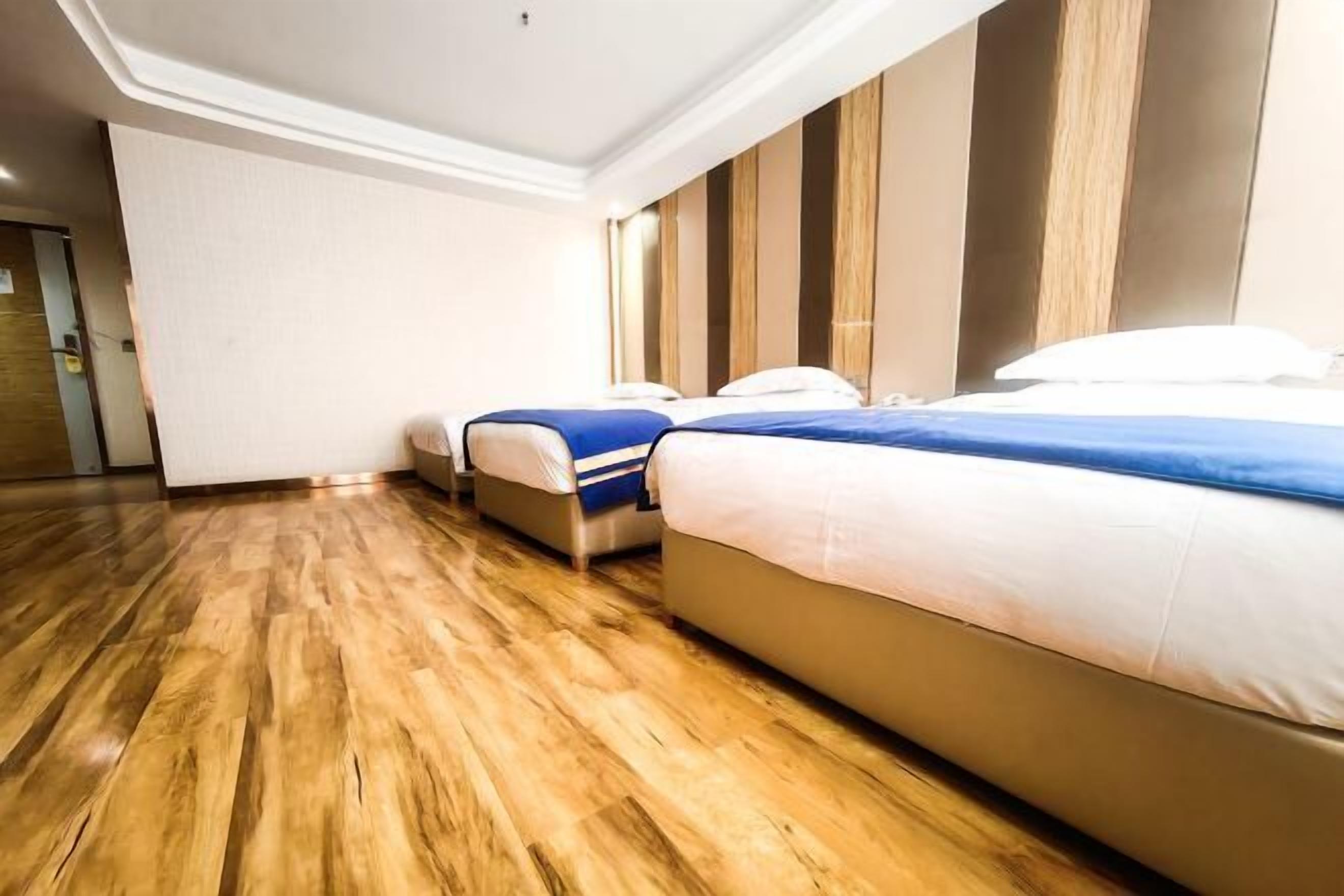 Habitación de hotel con dos camas, piso de madera y diseño moderno.