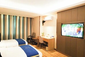 Quarto de hotel com duas camas, uma mesa, uma cadeira, uma televisão e cortinas.