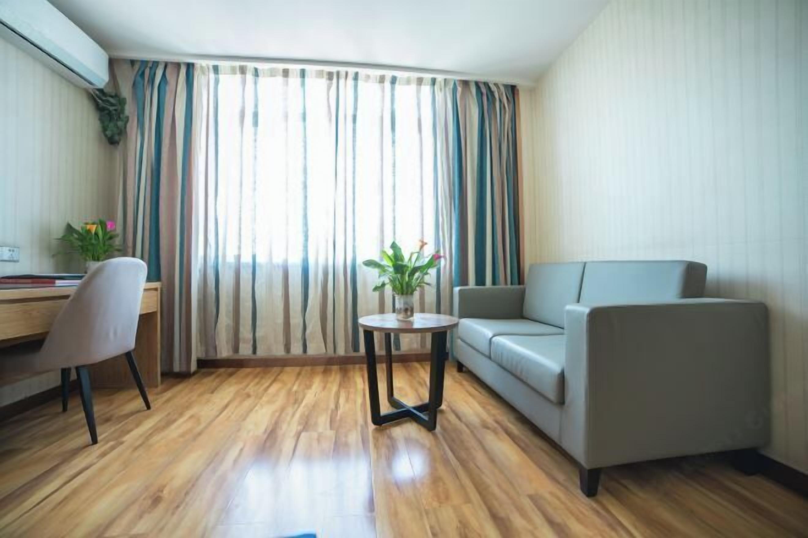 Una sala moderna con un sofá, una mesita redonda y un sillón.