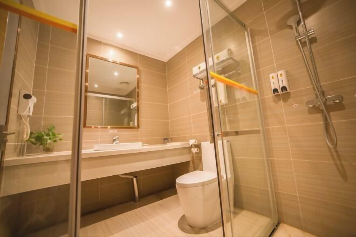 Un baño moderno con cabina de ducha de vidrio, inodoro y lavabo con espejo.