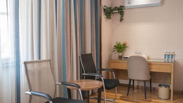 A hotel room with a wooden desk, two chairs, a potted plant, and an air conditioning unit. - Super 8 Hotel Zepu Fatong Park (Zepu)