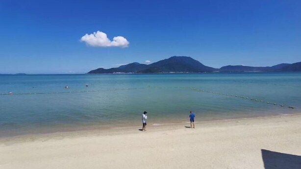 Una playa con agua cristalina y montañas a lo lejos.