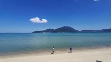 A beach with clear water, a sandy shore, and distant mountains.