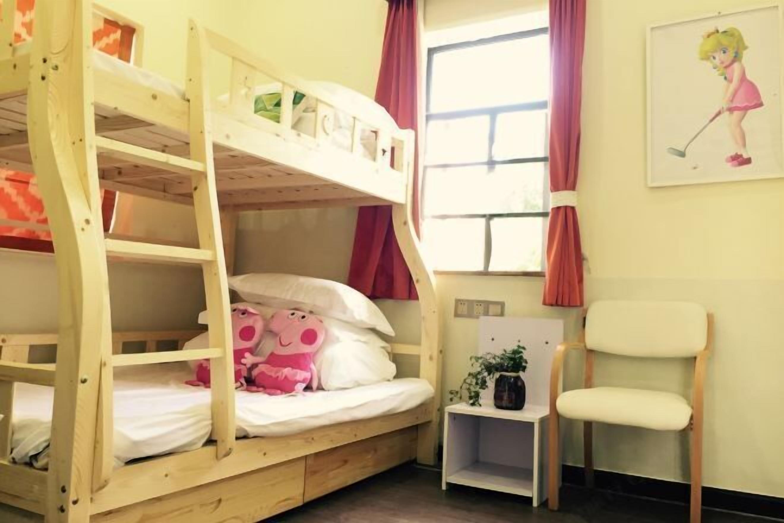 A bunk bed with a pink stuffed toy and a small table with a plant.