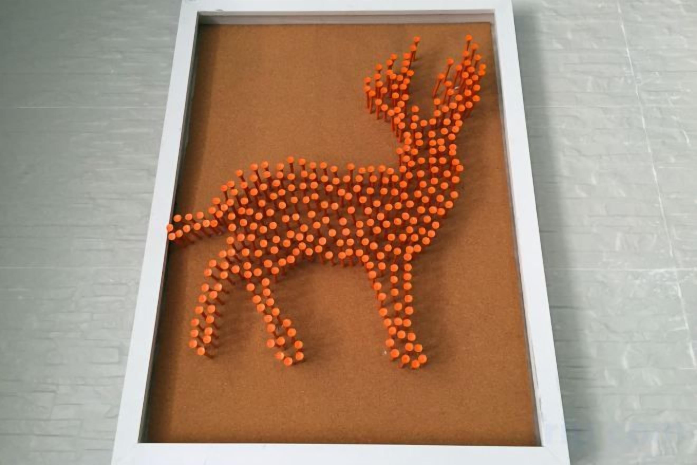 A framed artwork of a giraffe made from orange objects on a brown background.