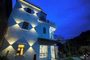 A multi-story building with a balcony and a well-lit entrance. - One More Homestay (Shenzhen)
