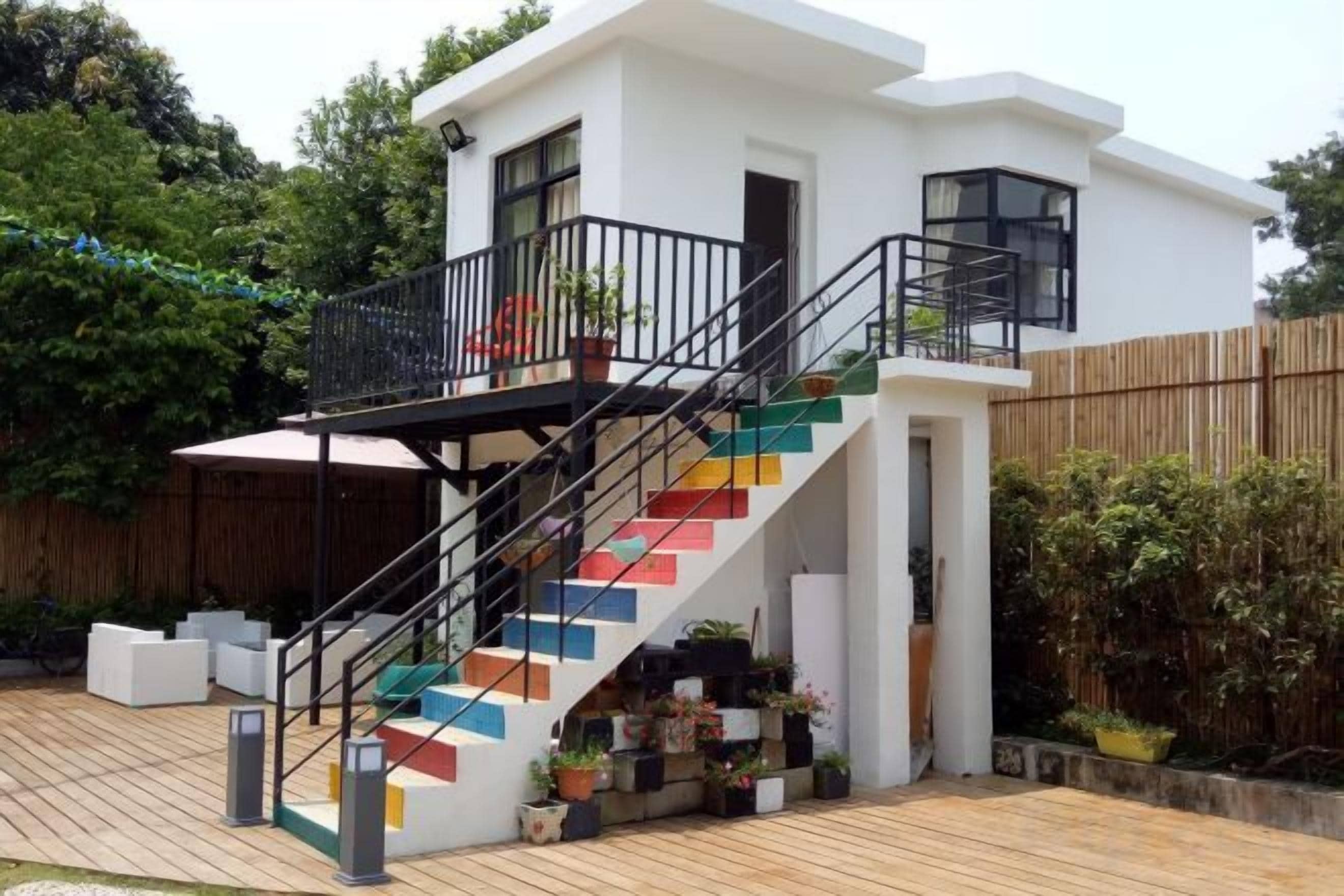 Ein modernes, zweistöckiges Haus mit einer Treppe mit farbenfrohen Stufen, einem Balkon und einer Holzterrasse.
